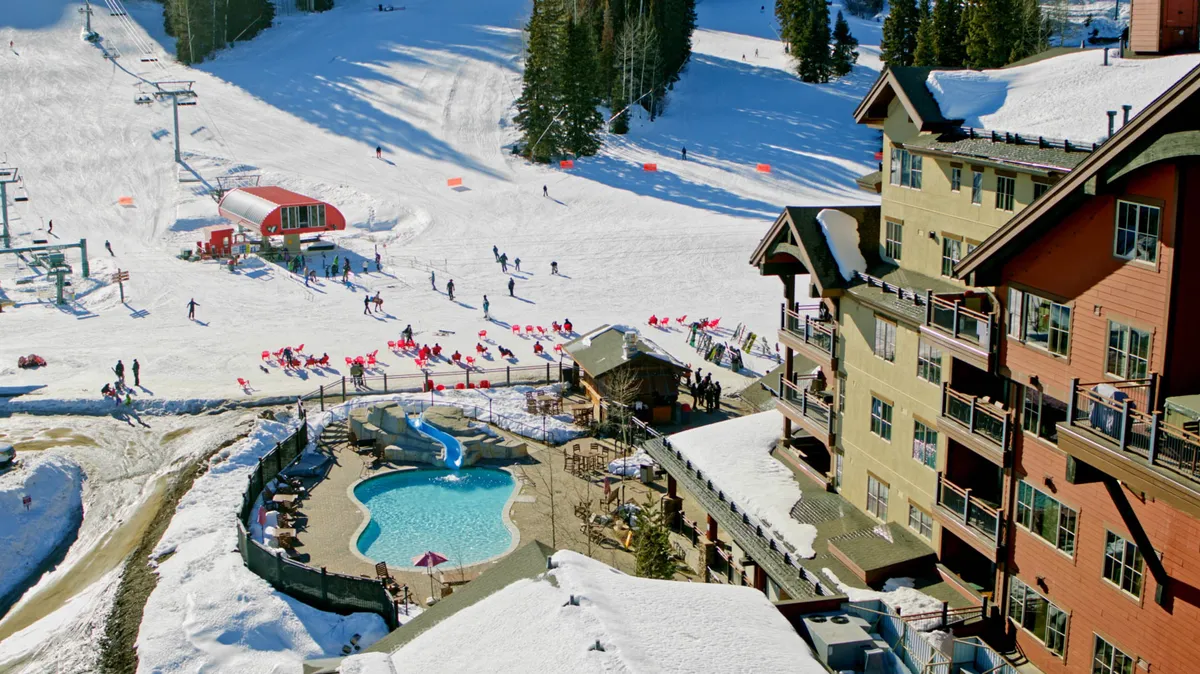 A lively exterior scene showing skiers on the slopes, a pool area, and the welcoming architecture of the resort lodge in the background. The image balances active winter fun with inviting relaxation spaces, hinting at après-ski socializing.