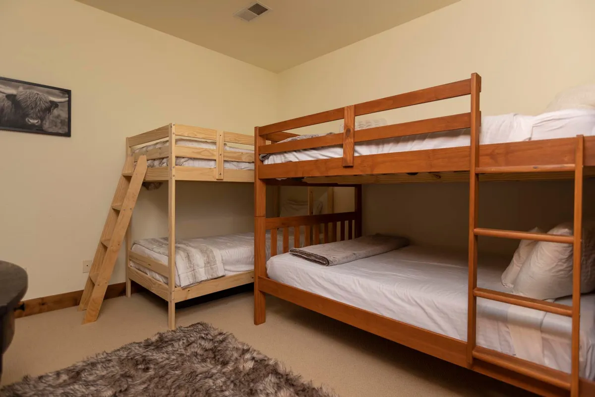This cozy interior showcases a set of inviting bunk beds, a soft rug, and tasteful wall art, creating a friendly and welcoming environment. The room feels perfect for intimate gatherings, storytelling, and creating shared memories, ideal for friends or families traveling together.